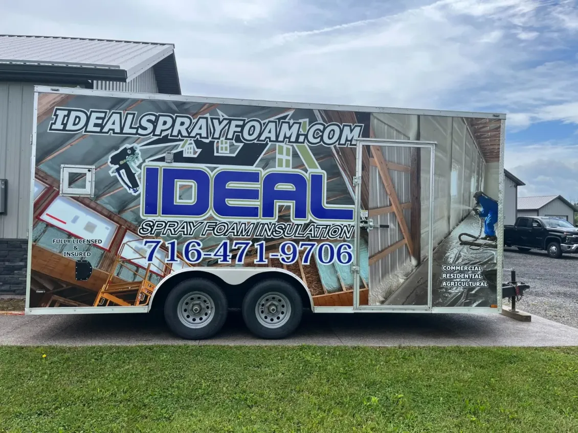 An ideal spray foam trailer is parked in front of a building.