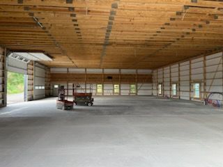 A large empty warehouse with a tractor parked inside of it.