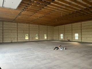 A large empty building with a lot of windows and a concrete floor.