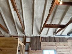 The ceiling of a building with wooden beams and insulation.