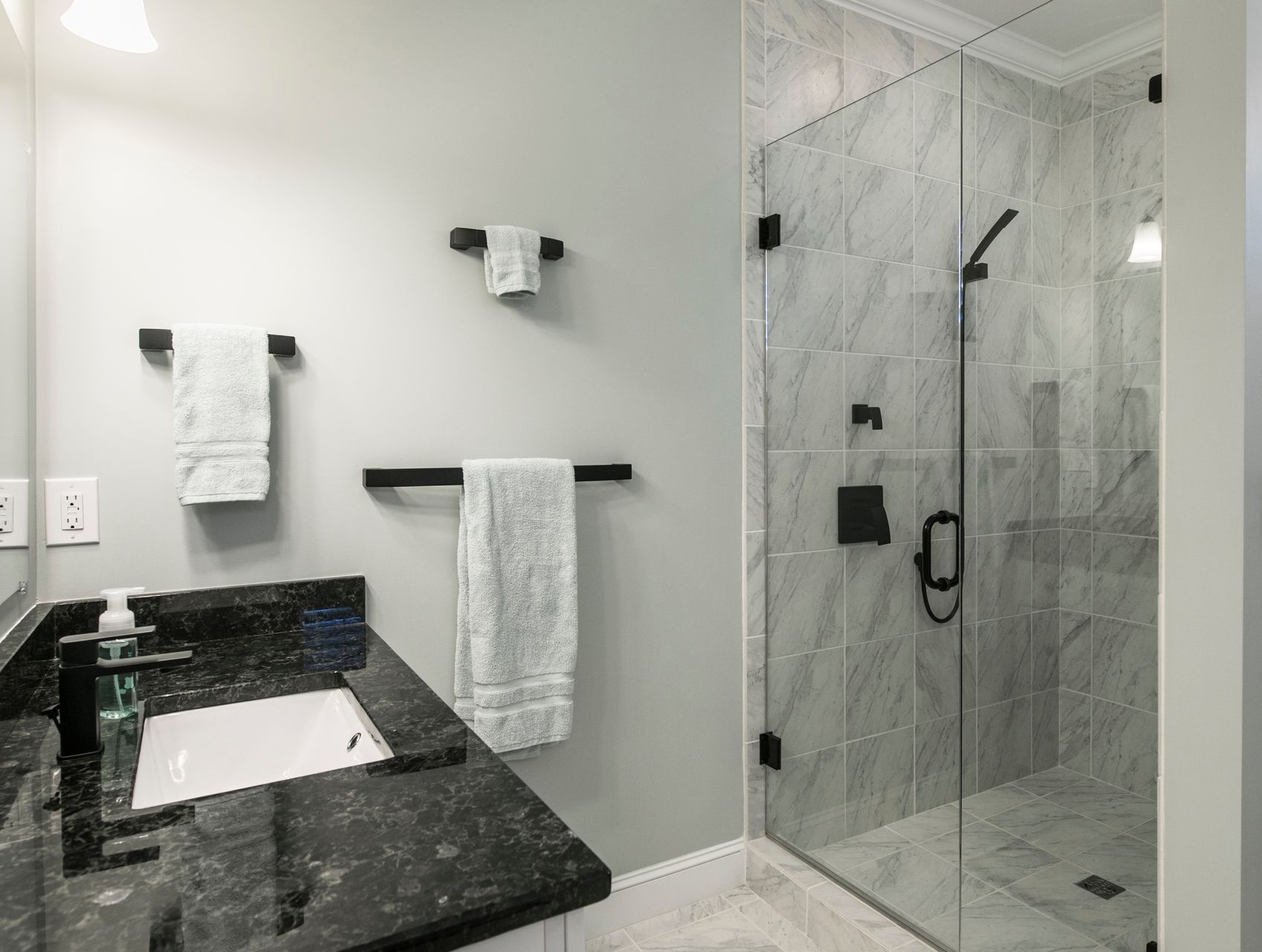 A bathroom with a sink and a walk in shower.