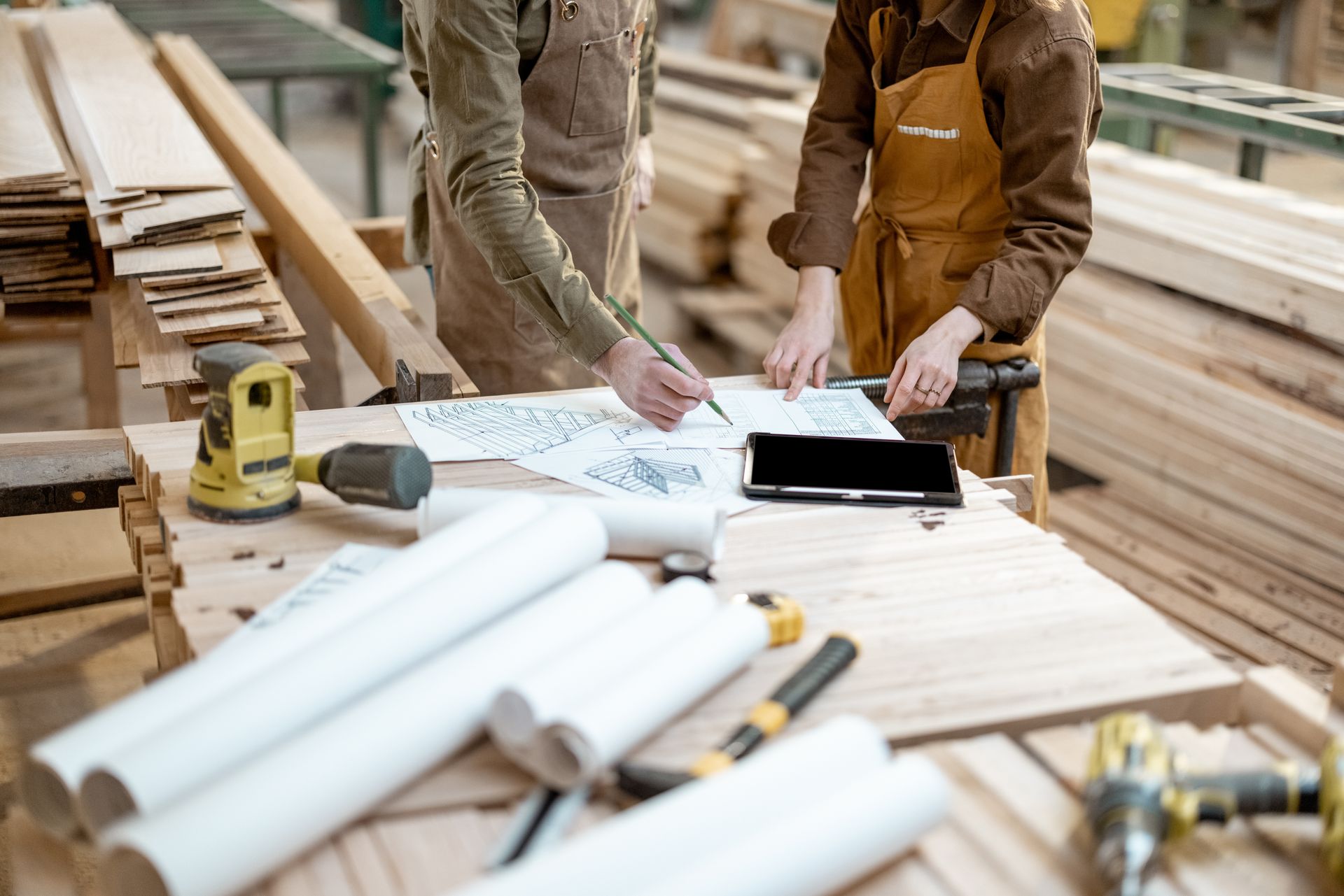 Two carpenters are working on a project in a woodworking shop.
