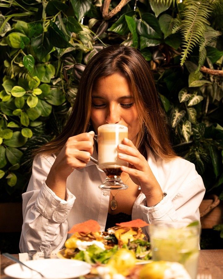 Uma mulher está sentada à mesa tomando uma xícara de café, na cafetaria em braga