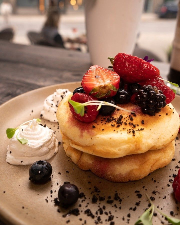 Uma pilha de panquecas com frutas e chantilly por cima fazem parte de um Bruch