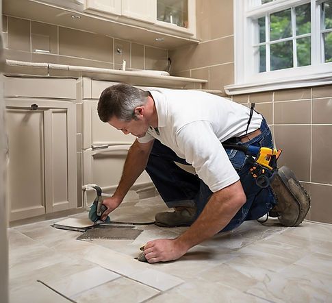 Worker cutting tile on a bathroom floor with a handheld saw, wearing a tool belt.