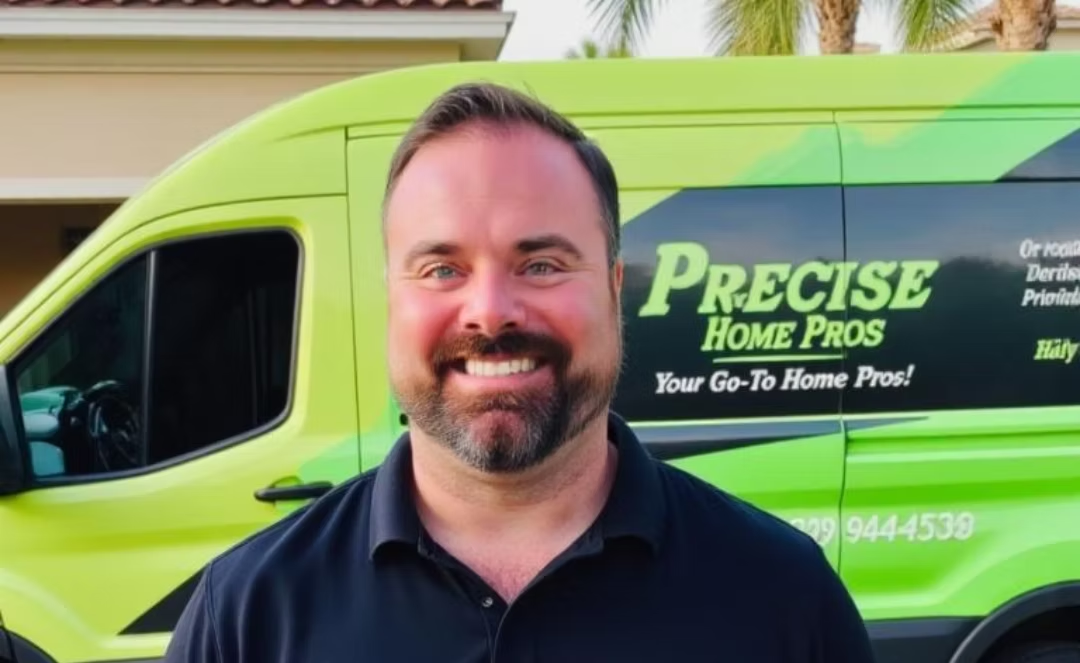 Smiling man standing before a lime-green Precision Home Pros van