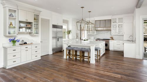Bright white kitchen with island, wooden floor, and built-in cabinets in a spacious open layout