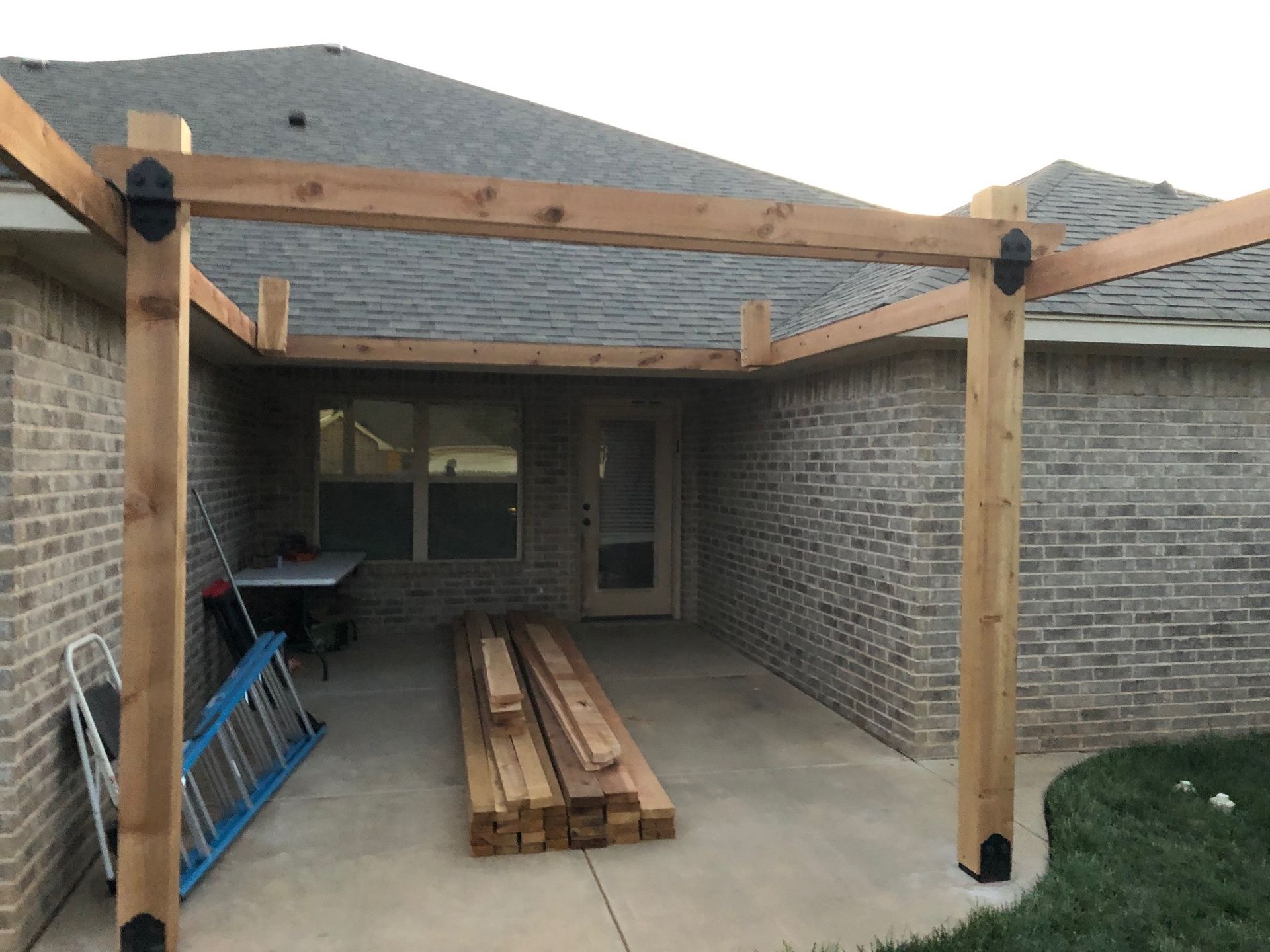 A wooden structure is being built on the side of a brick house.