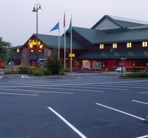 Empty parking lot in front of a Gander restaurant at dusk, with flags and lit windows