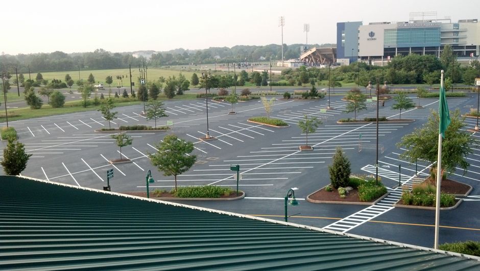 Empty parking lot beside a modern building, with trees and painted parking lines at dusk