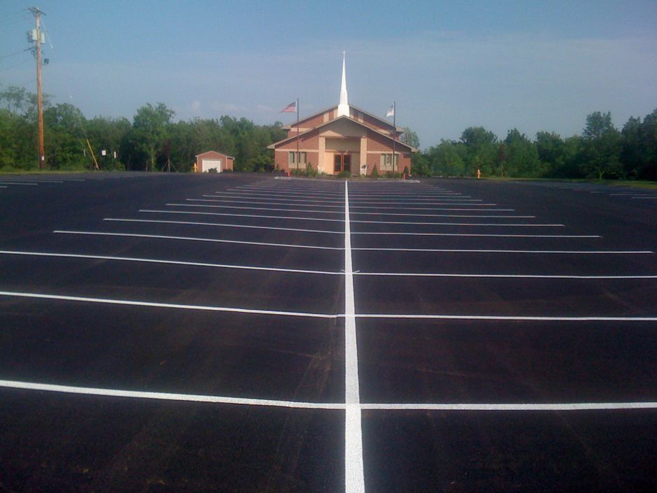 Empty parking lot with white lines leading to a small church in the distance.