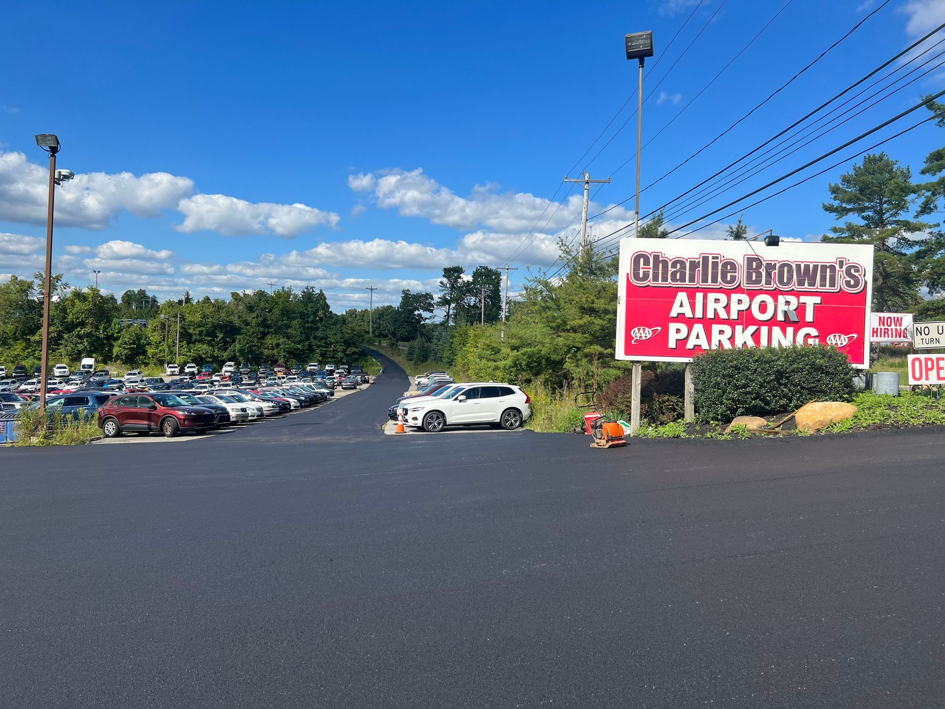 Charlie Brown's Airport Parking sign beside a large parking lot on a sunny day