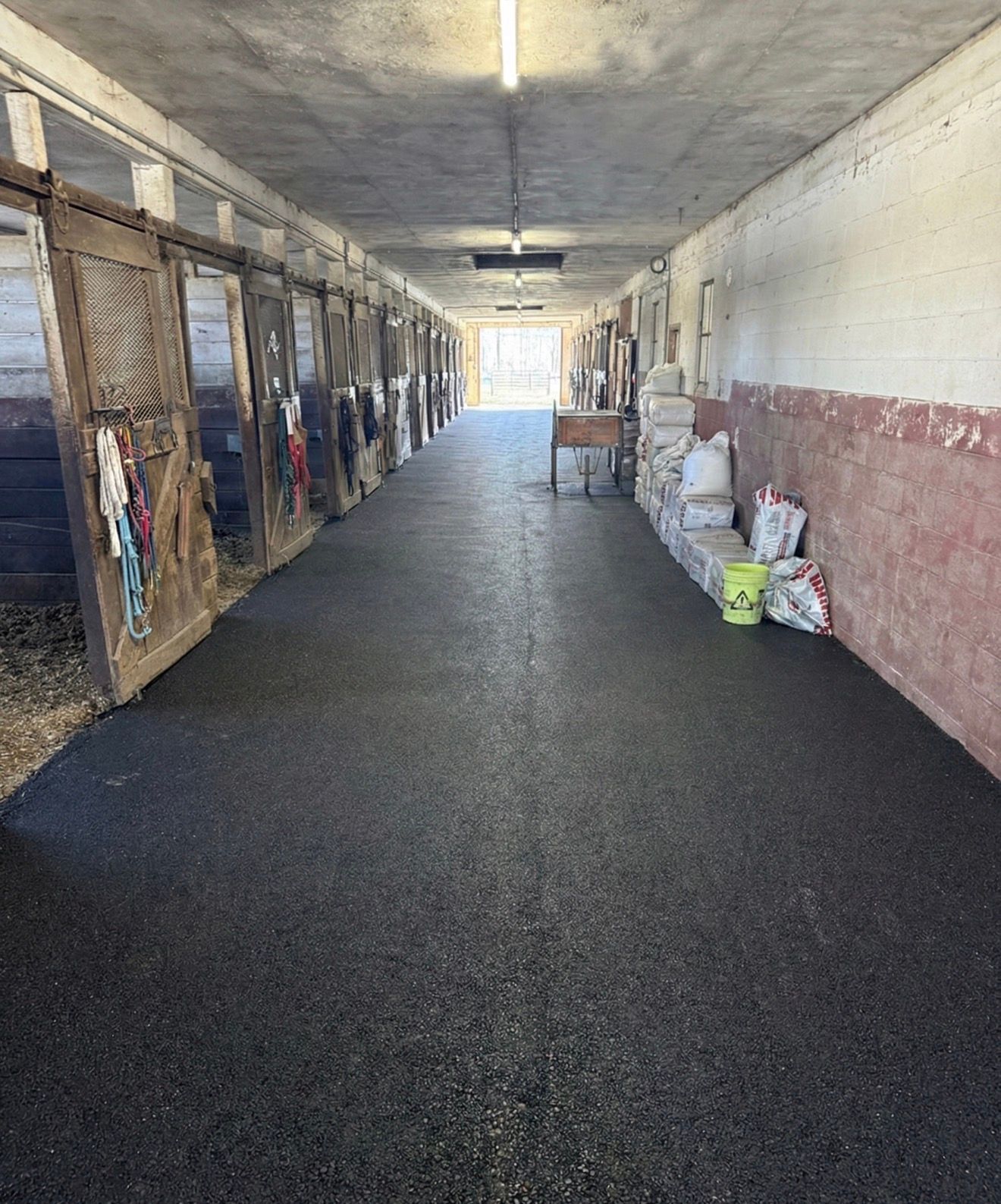 Long indoor corridor with stalls on the left and bags stacked along the right wall