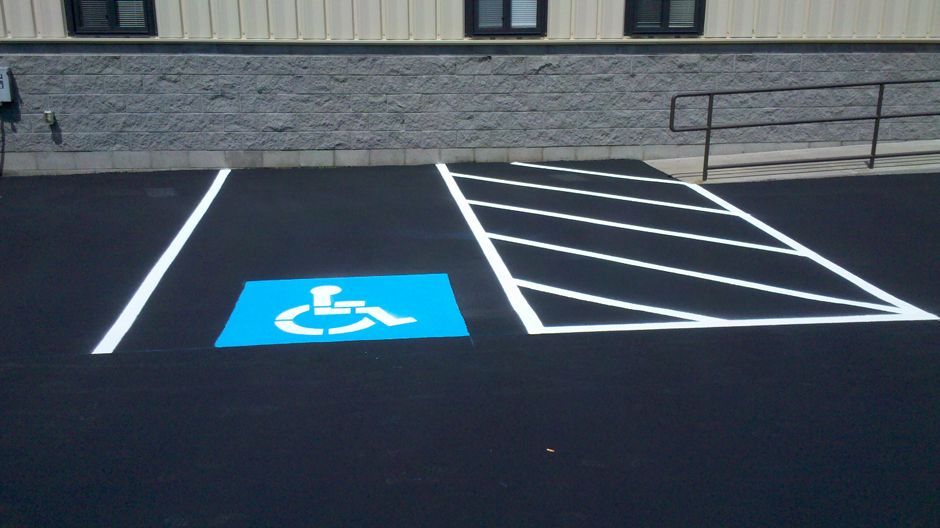 Accessible parking space with blue handicap symbol and adjacent striped loading zone in a lot