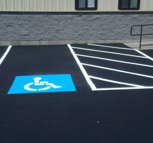 Accessible parking space with blue wheelchair symbol and white striped access aisle on black pavement.