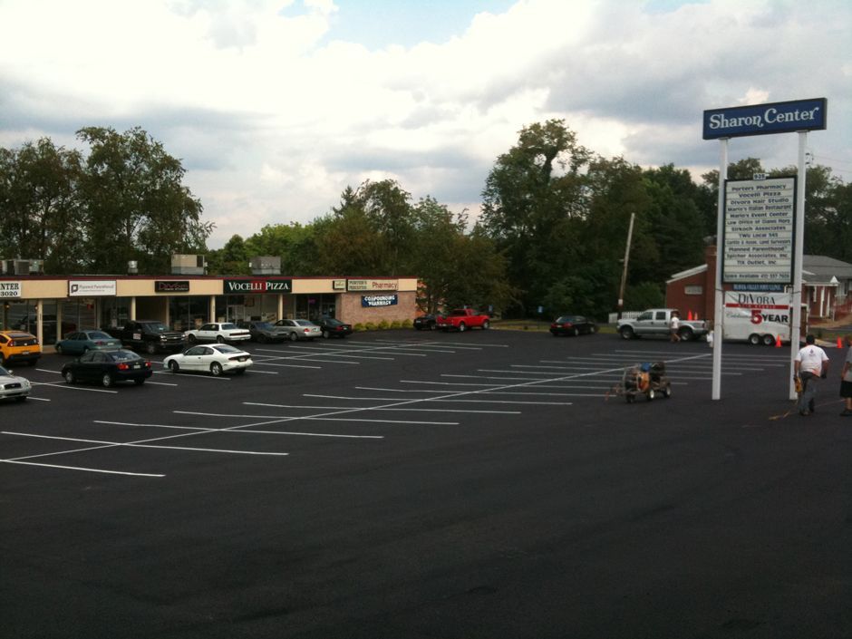 Shopping center parking lot with few cars, storefronts, and a Shannon Centre sign under cloudy sky