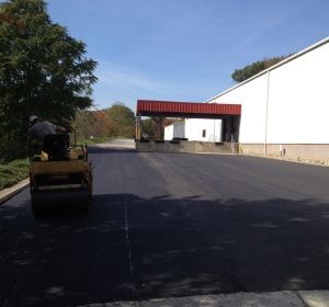 Paved industrial roadway with a worker on a small vehicle under a red overhead structure