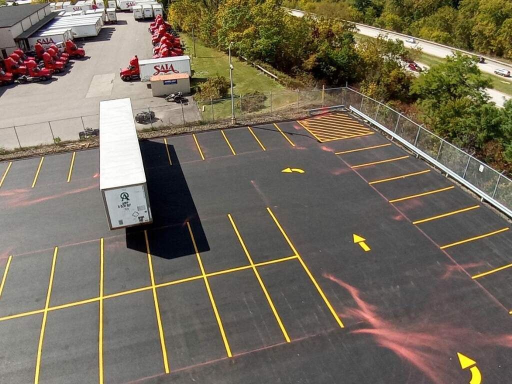Empty truck loading dock with marked parking spaces and a white trailer in a paved lot