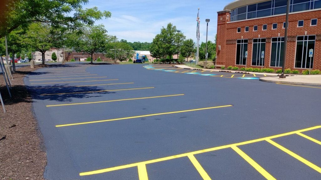 Empty parking lot with yellow painted lines beside a red brick building under a clear sky