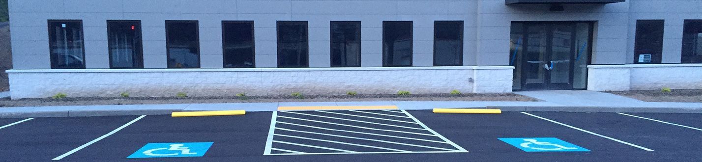 Parking lot with blue accessible spaces and tactile paving leading to a building entrance
