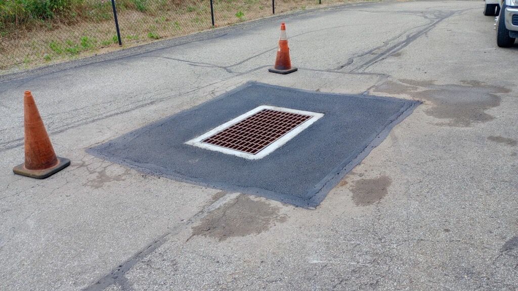Roadside storm drain cover in asphalt.