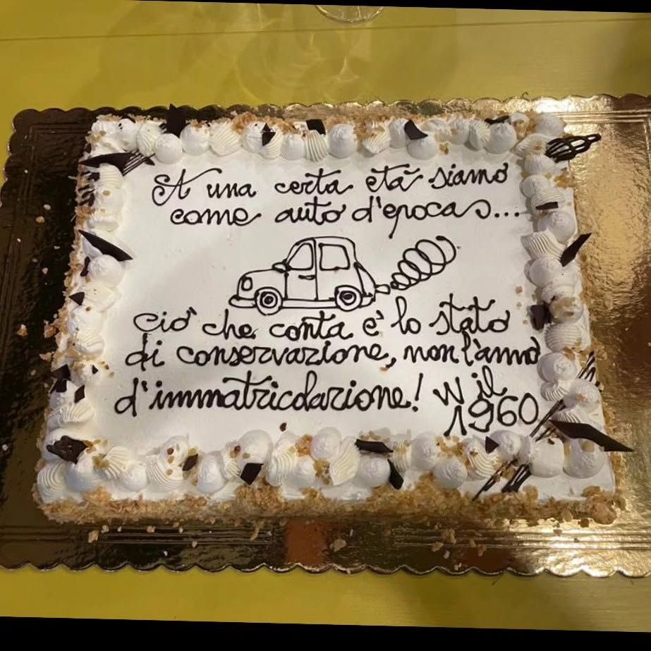 Torta rettangolare con glassa bianca e scritta in cioccolato su vassoio dorato