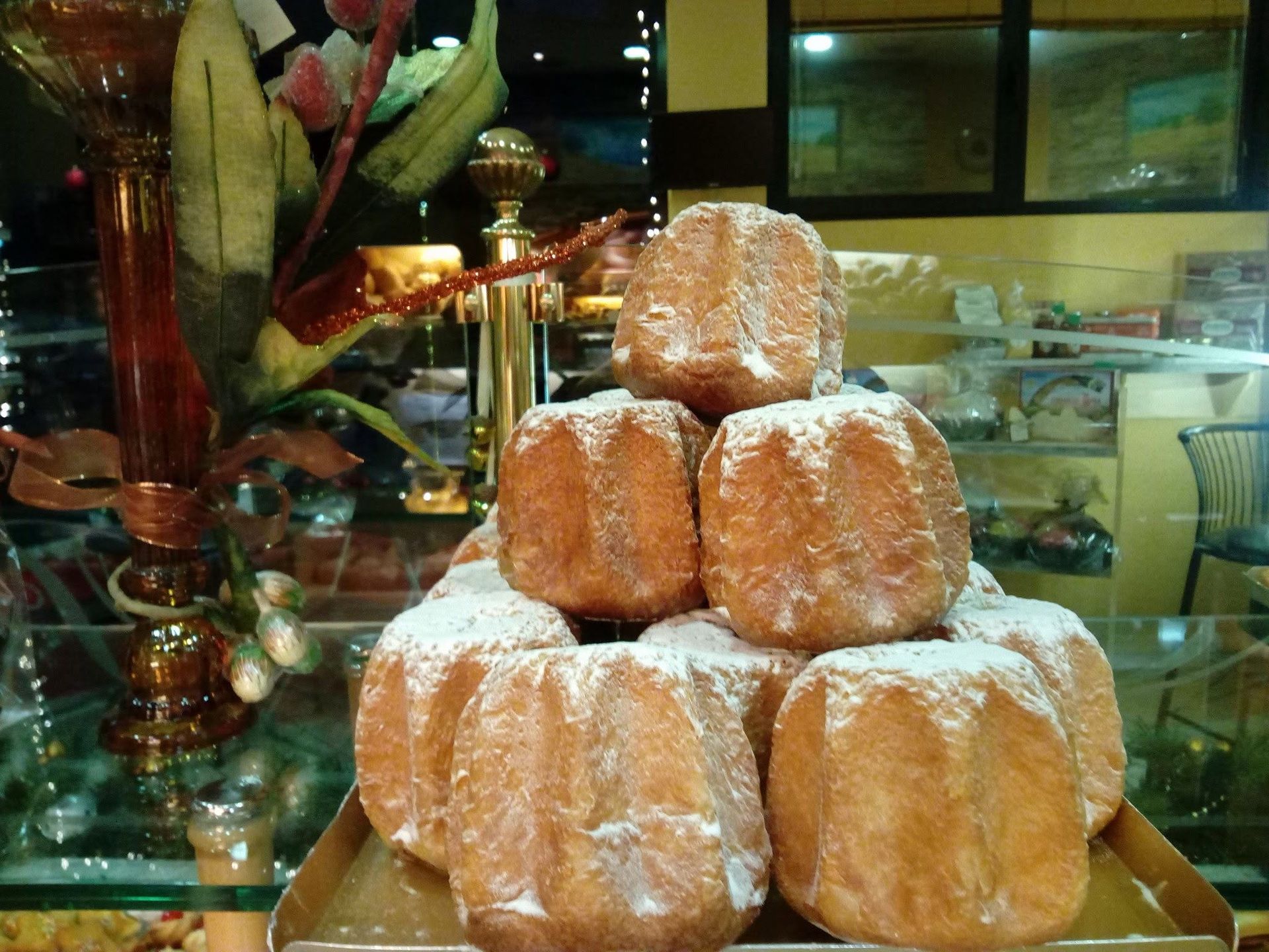 Pila di pasticcini ricoperti di zucchero a velo su un vassoio nella vetrina di una pasticceria.