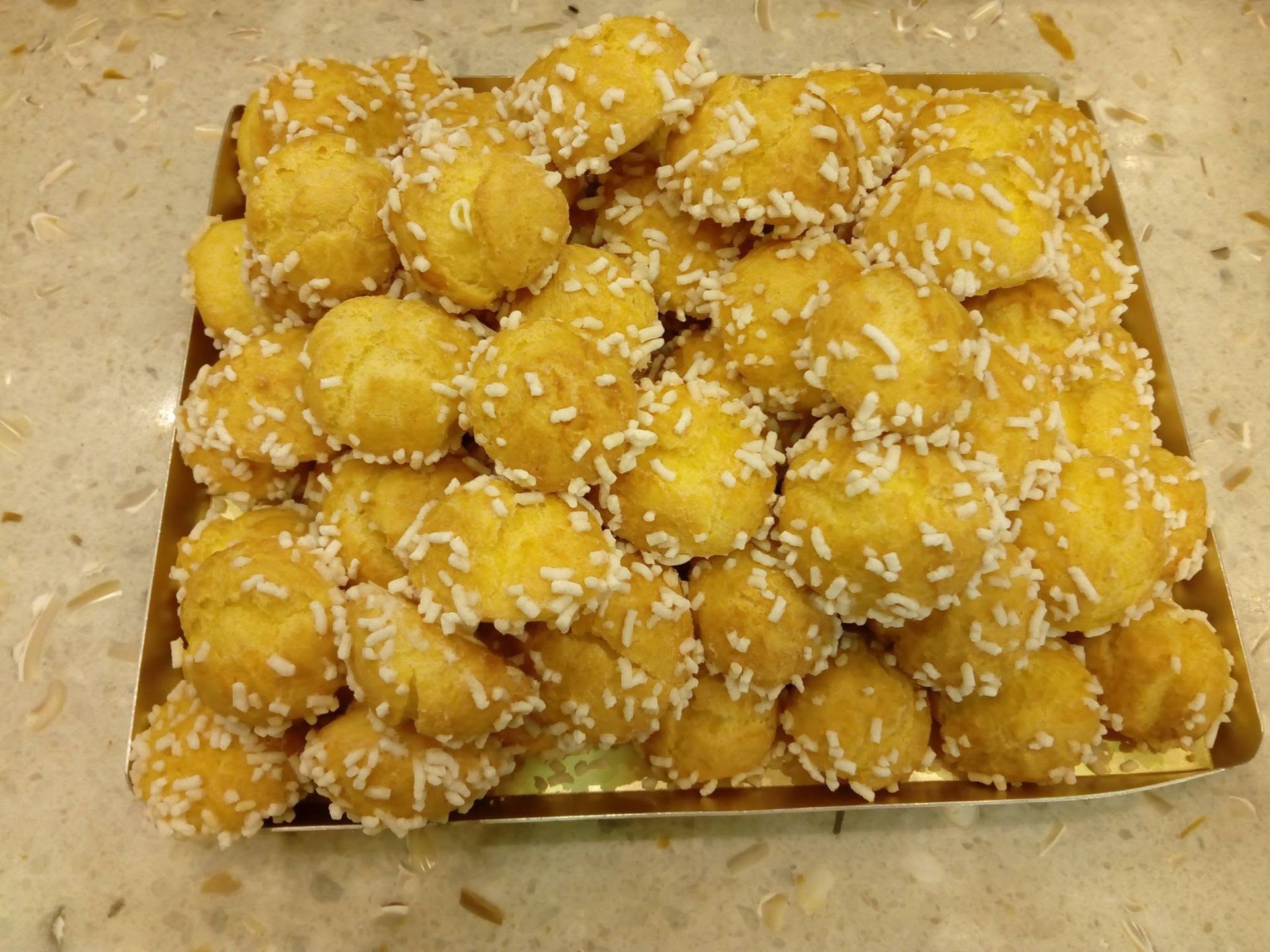 Vassoio di palline di dessert fritte dorate, cosparse di cocco grattugiato.