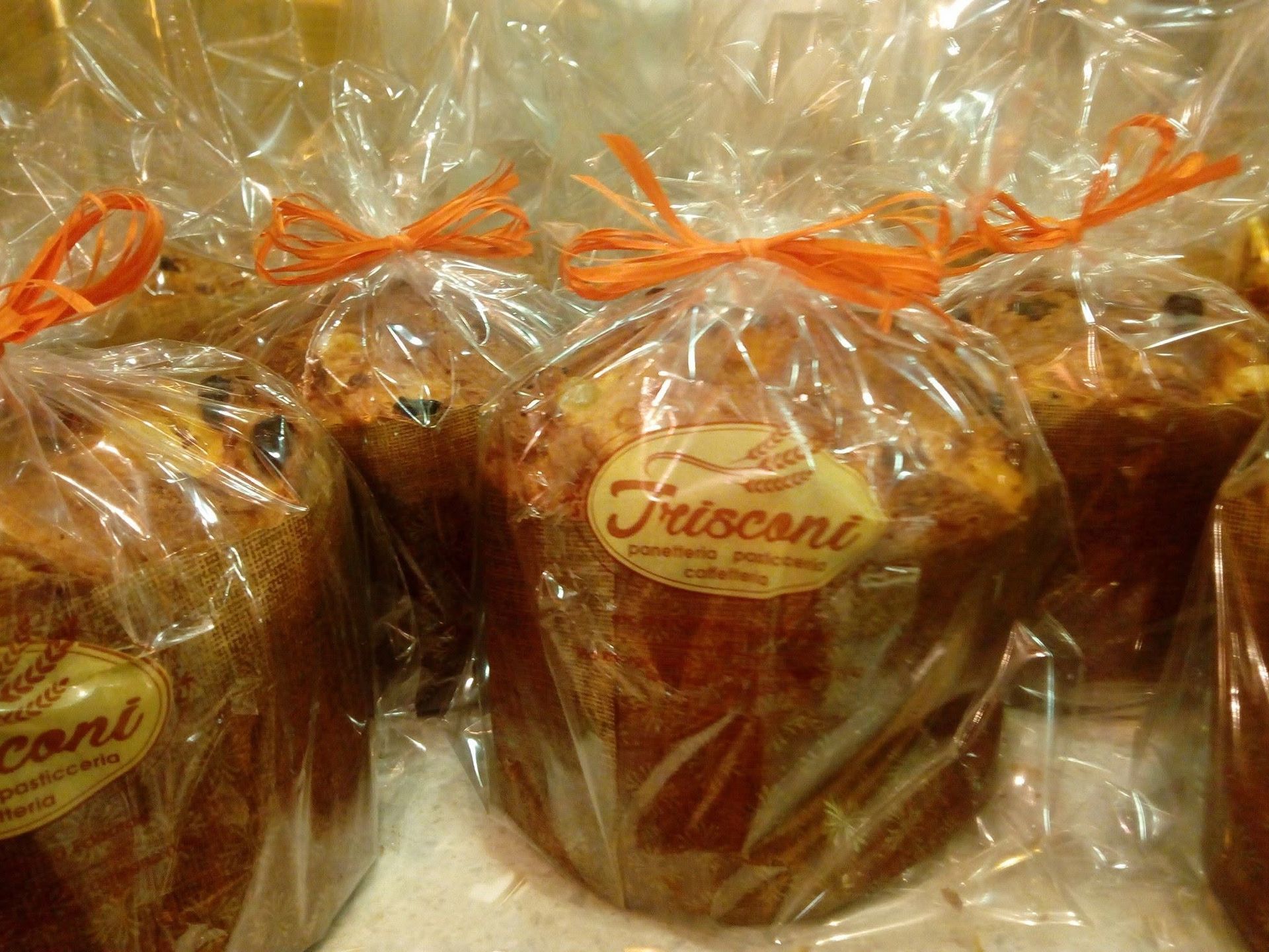 Pagnotte di pane frisone avvolte in plastica trasparente con lacci arancioni su uno scaffale di un negozio.