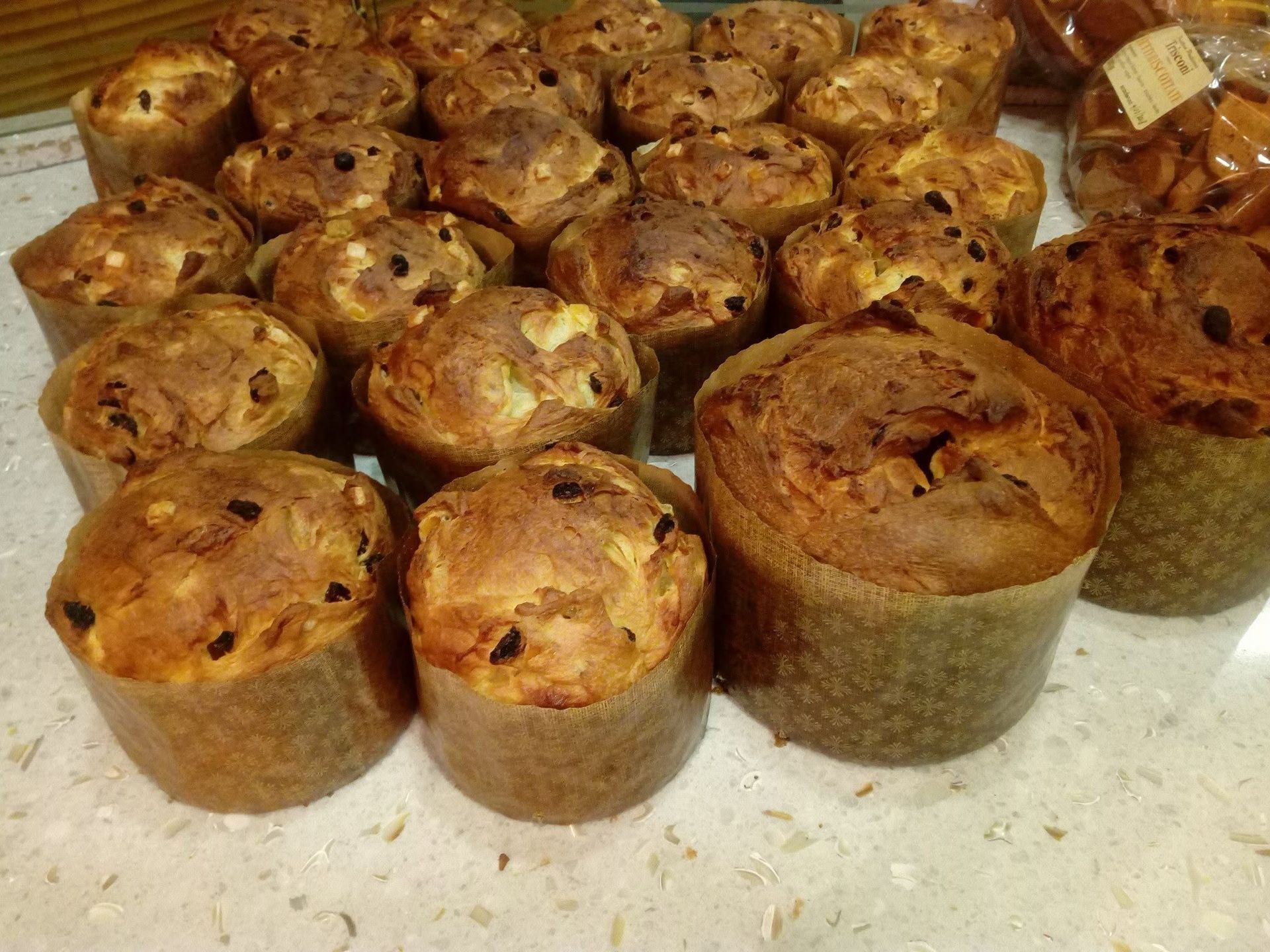 Vassoio di muffin o mini-panini assortiti, cotti al forno e con la superficie dorata, disposti uno accanto all'altro.