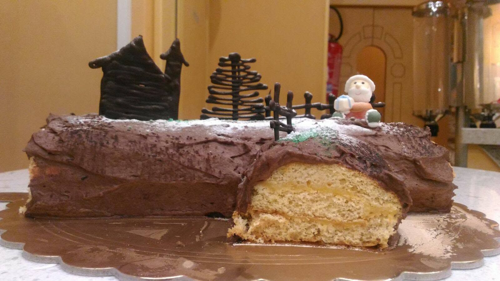 Torta al cioccolato glassata con una fetta tagliata, decorata con piccole decorazioni natalizie su un tavolo