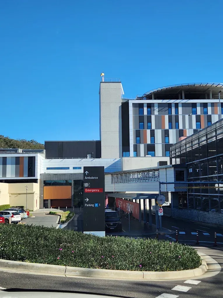 Hospital building with multi-story sections, helipad, and signage. Sunny day.