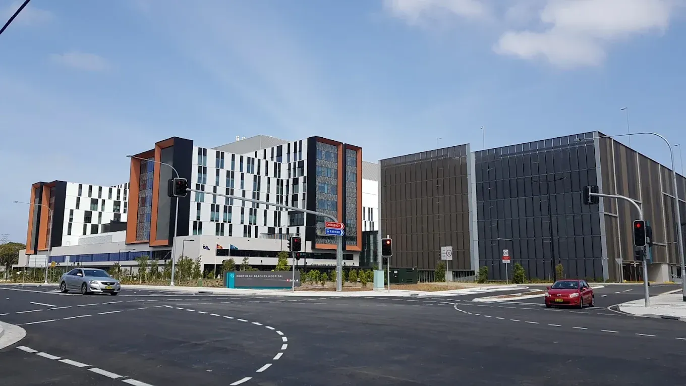Modern buildings at a street intersection; cars, blue sky.