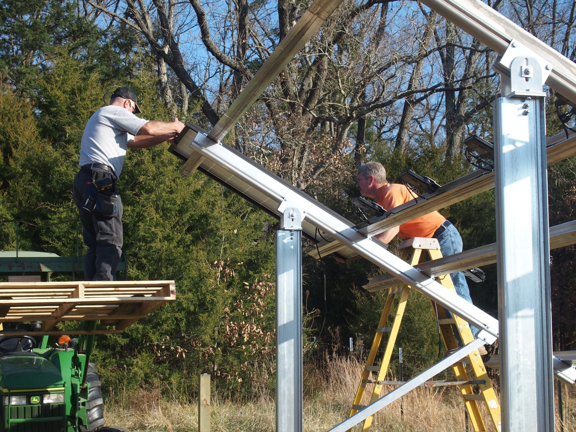 Two men are working on a metal structure in a field