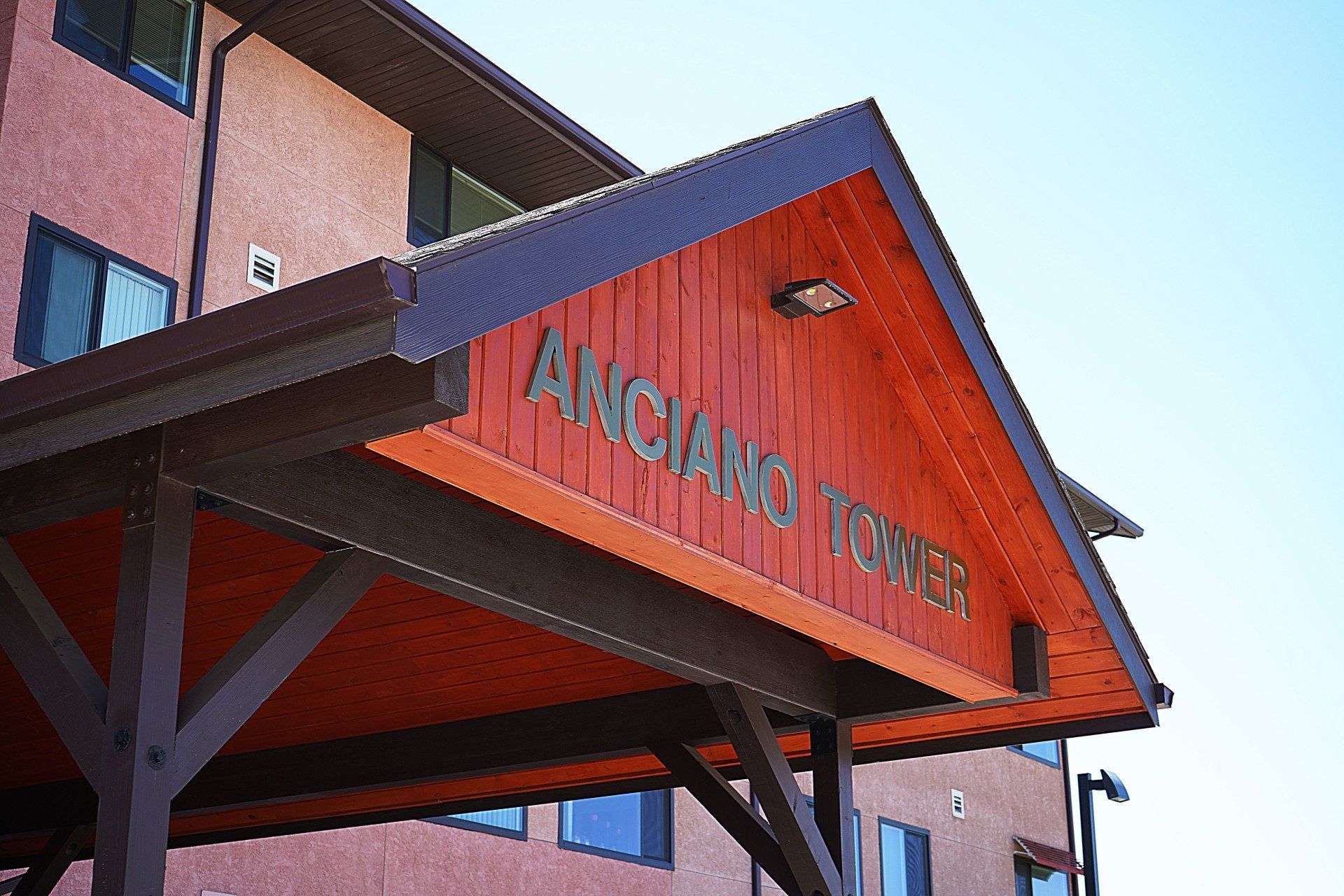 A low-angle view of a building entrance with a wooden overhang featuring the text 