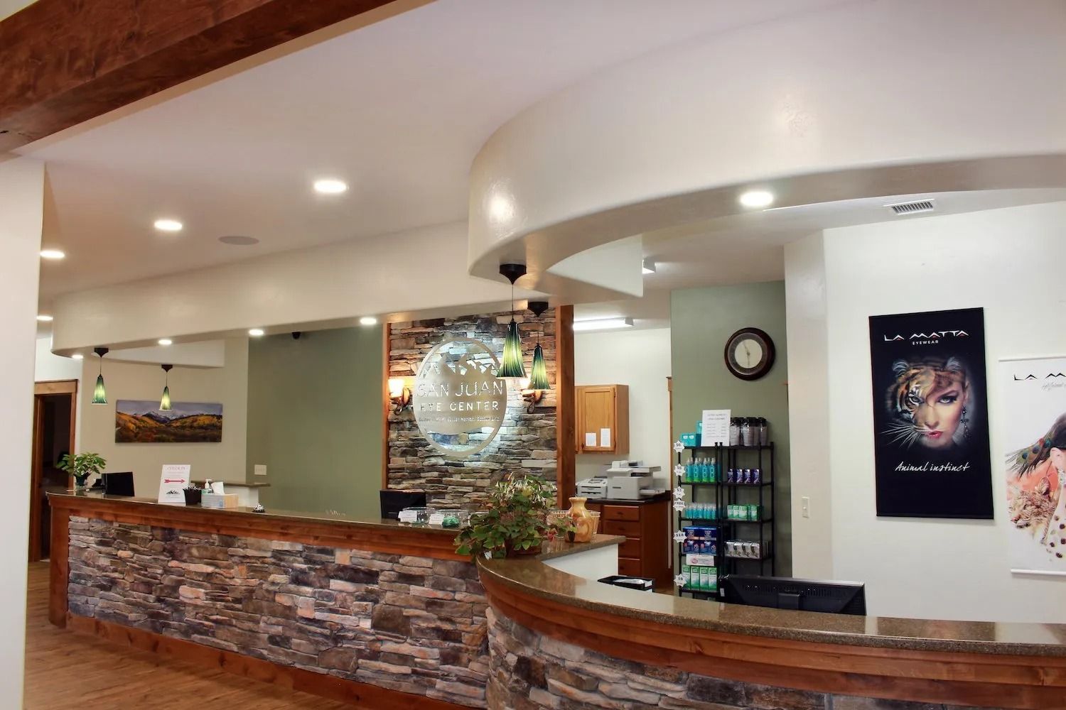 A stone-accented reception desk inside a salon, featuring recessed lighting, product displays, and framed wall art.