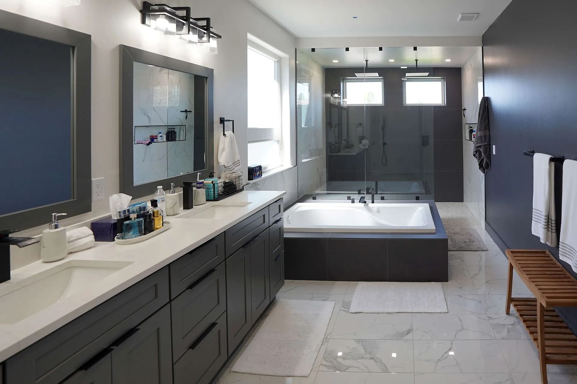 Modern primary bathroom with a double vanity, large soaking tub, walk-in glass shower, and marble flooring.