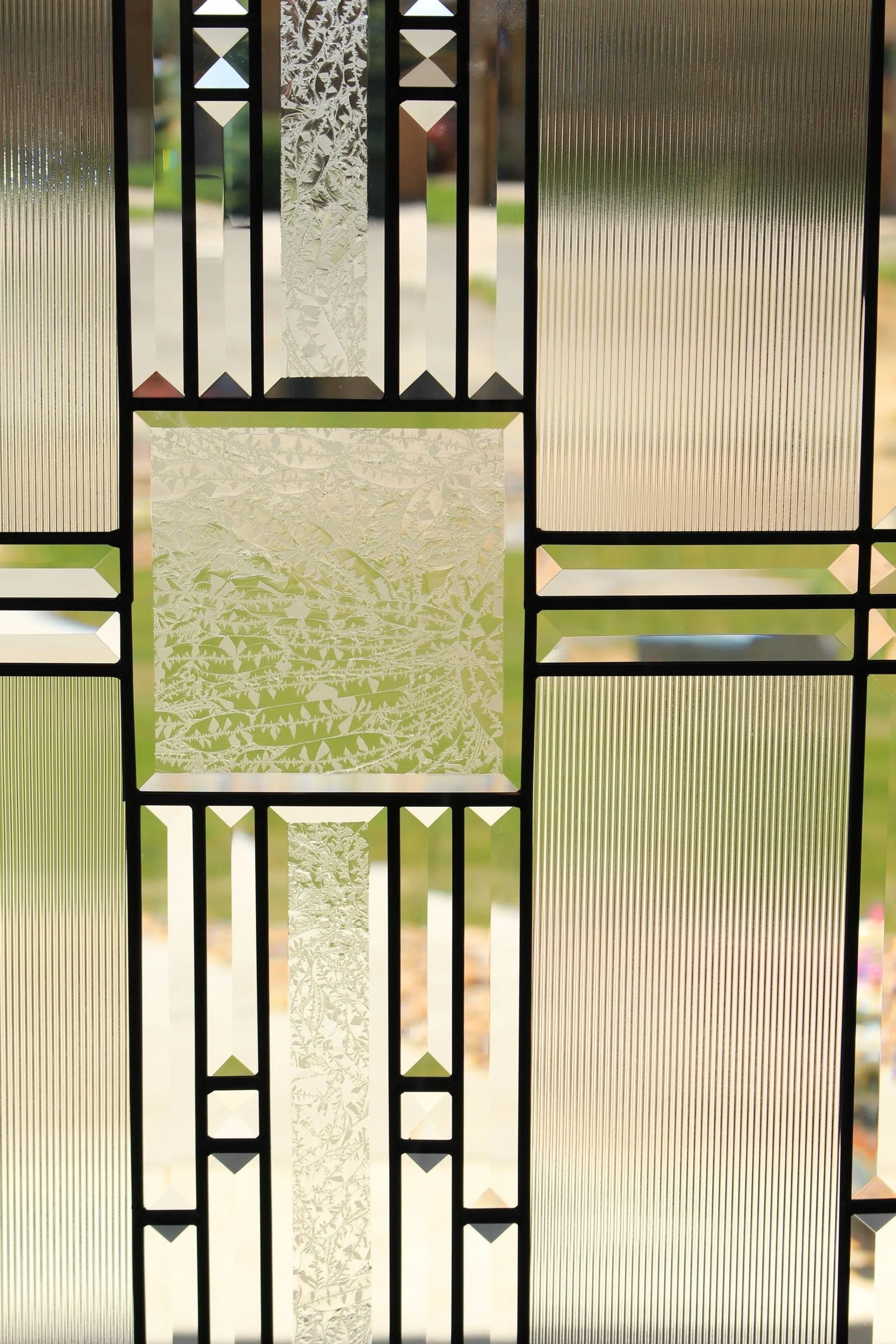 A close-up of decorative, leaded glass window panes with various textures and clear rectangular sections.