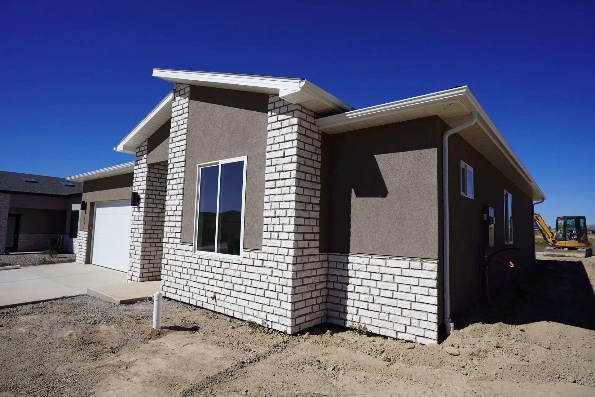 New house exterior with stone and stucco walls under a clear blue sky