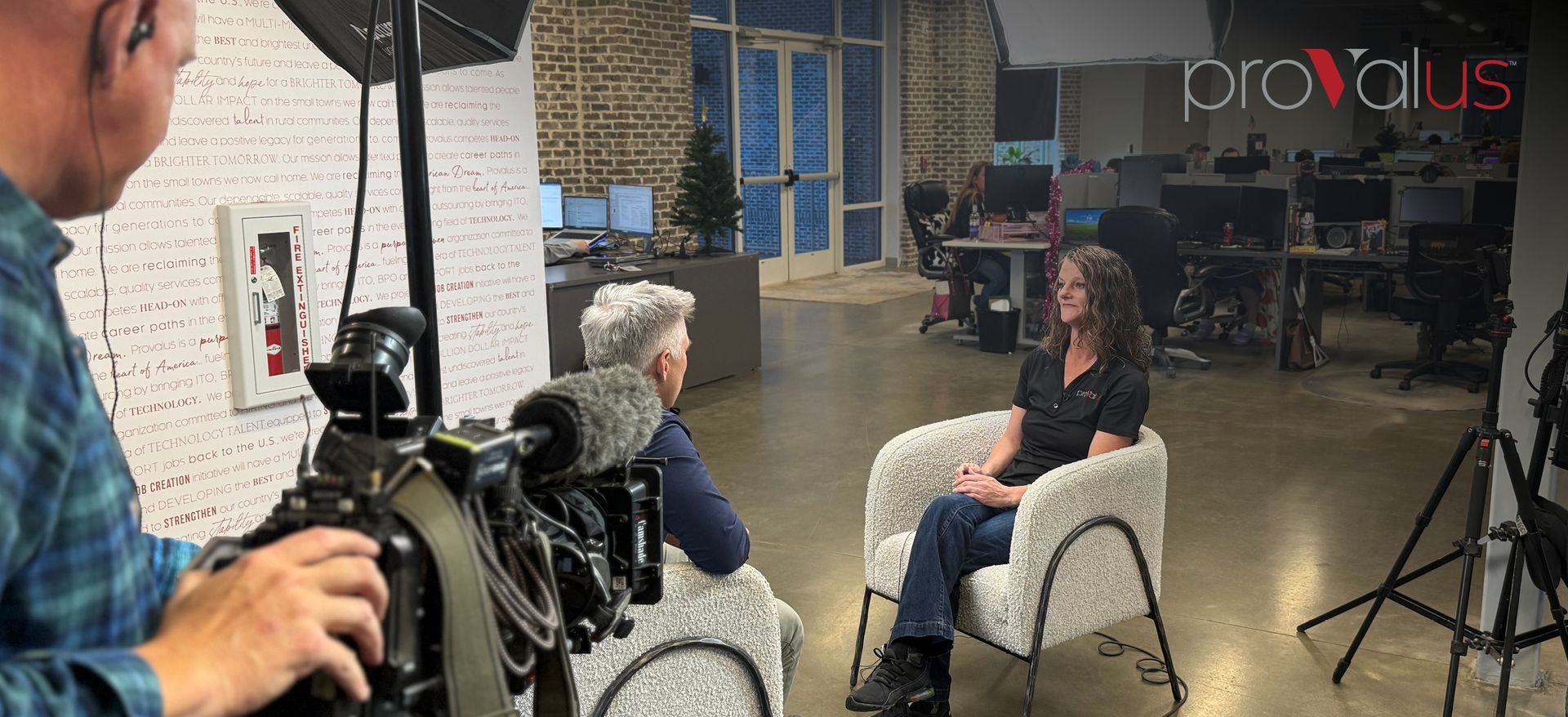 Interview setup in a studio with cameras, lights, and two people seated and talking.