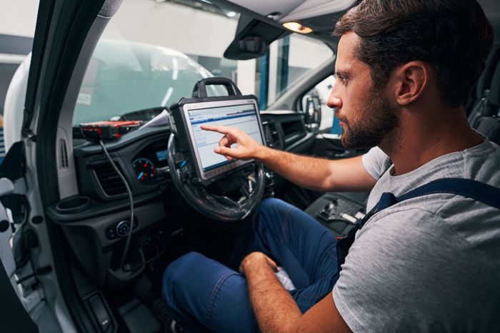 Man using a tablet inside a car, seated in the driver’s seat with the dashboard visible. | Graybeal's Auto Repair, Inc.
