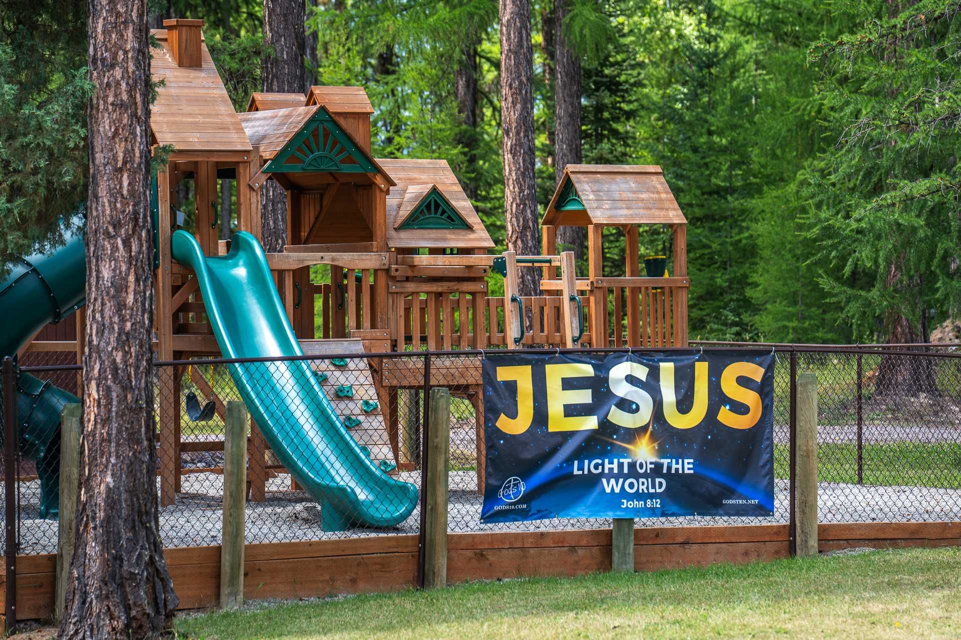 Playground with wooden structure, green slide, and banner that reads 