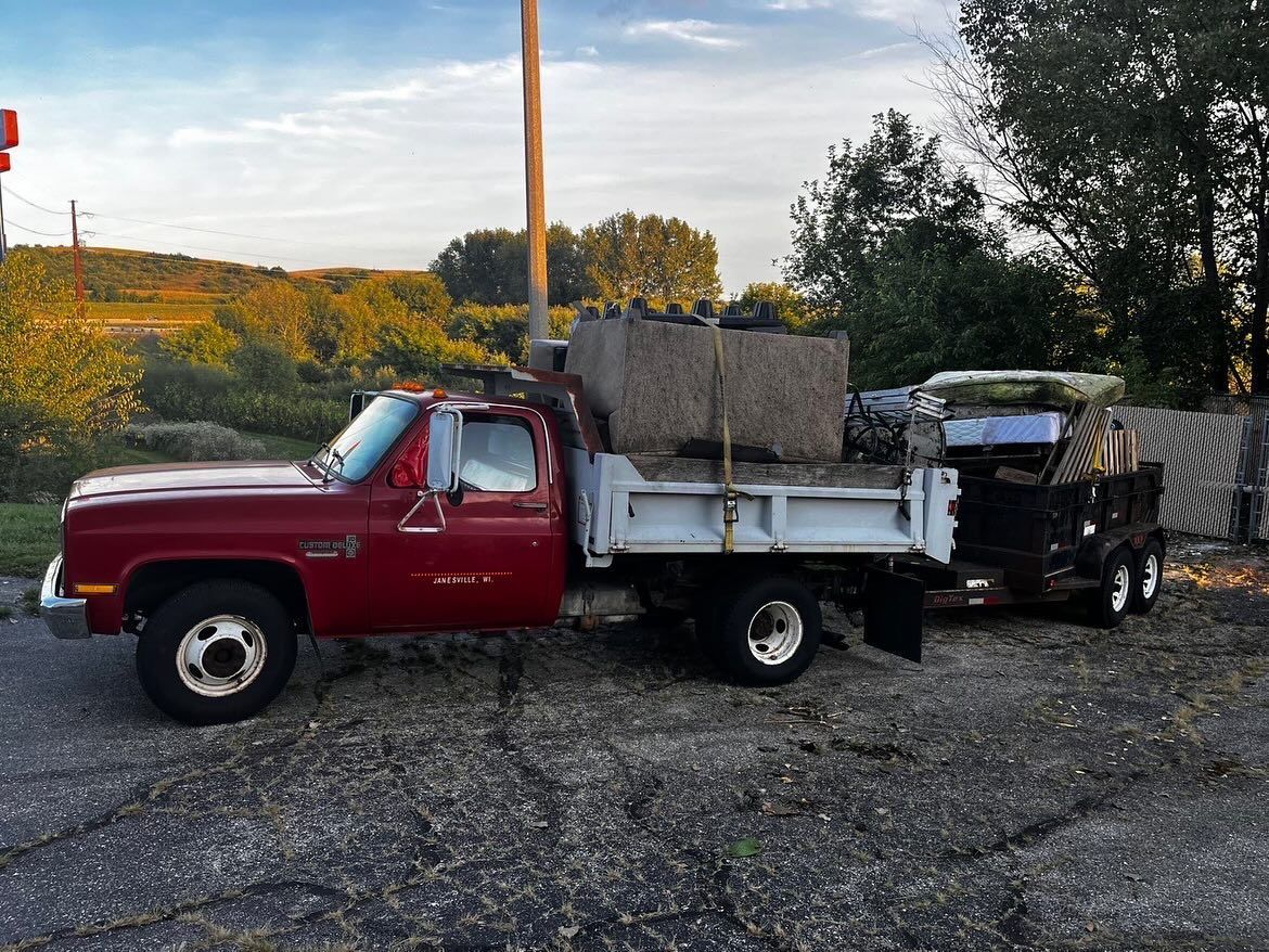 Red dump truck loaded with concrete blocks parked on gravel at sunset