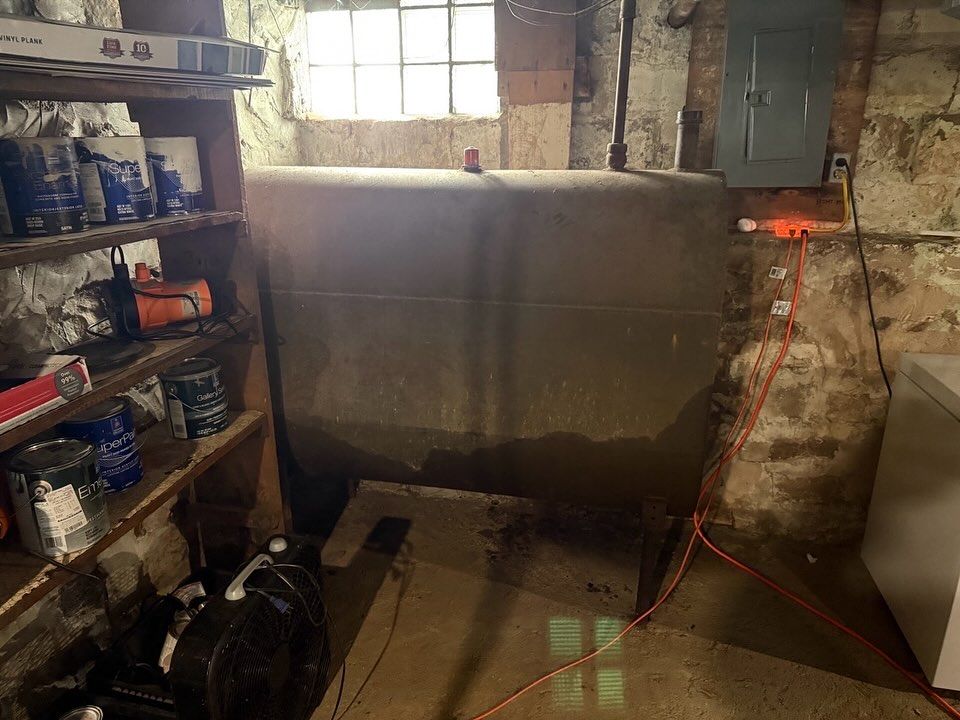 Dim basement with shelves, a wet concrete wall, and an extension cord near a window.