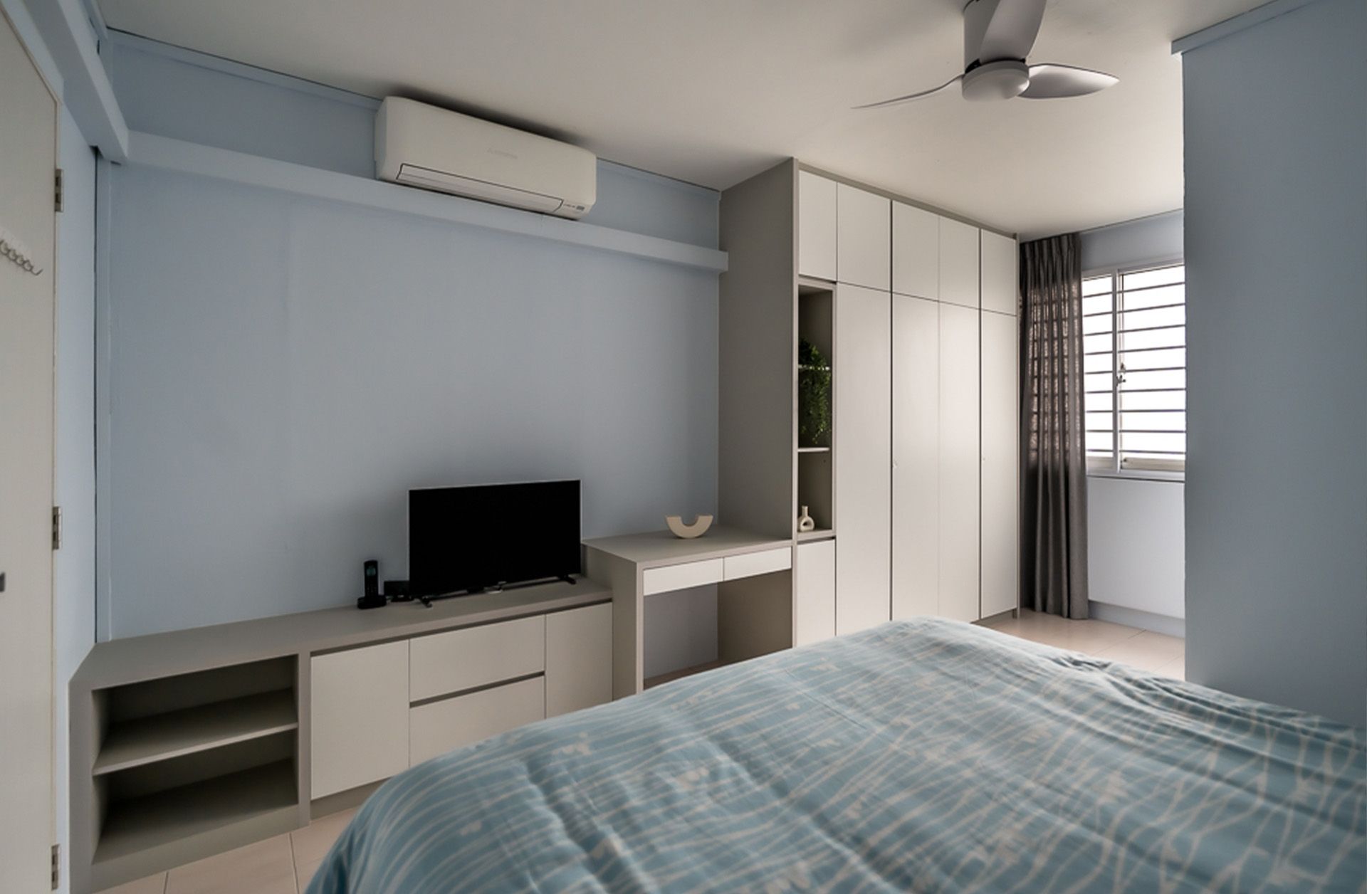 A bedroom with a bed a television and a ceiling fan