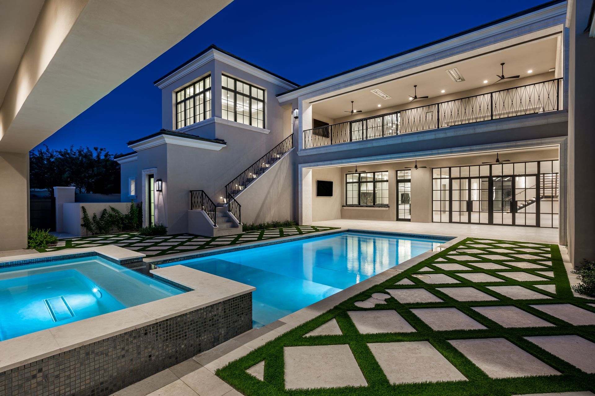 Modern luxury house with lit pool and patio at dusk