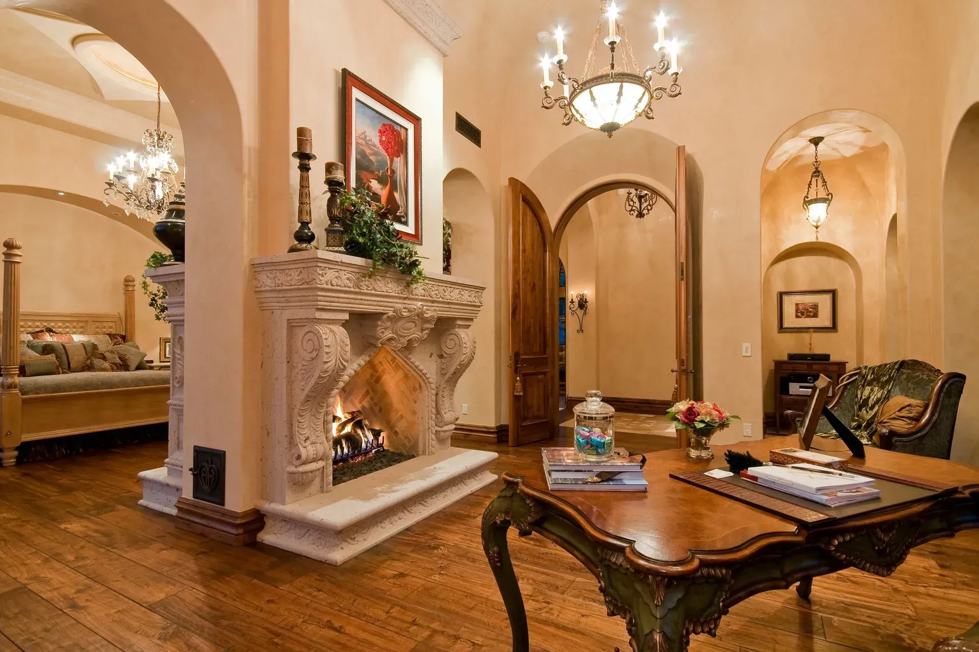 Ornate room with fireplace, arched doorways, chandelier, and a desk.