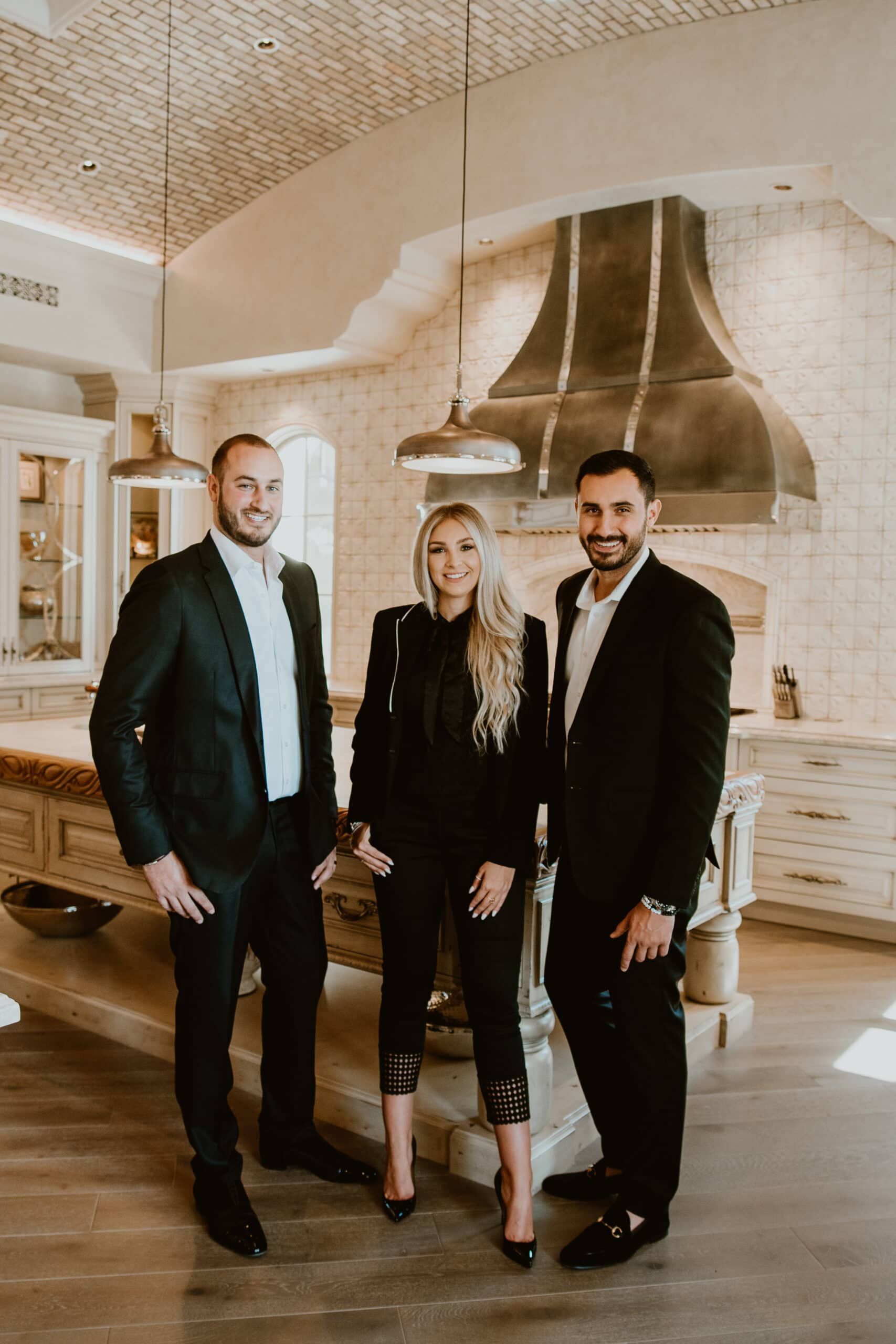 A group of three people standing next to each other in a kitchen.