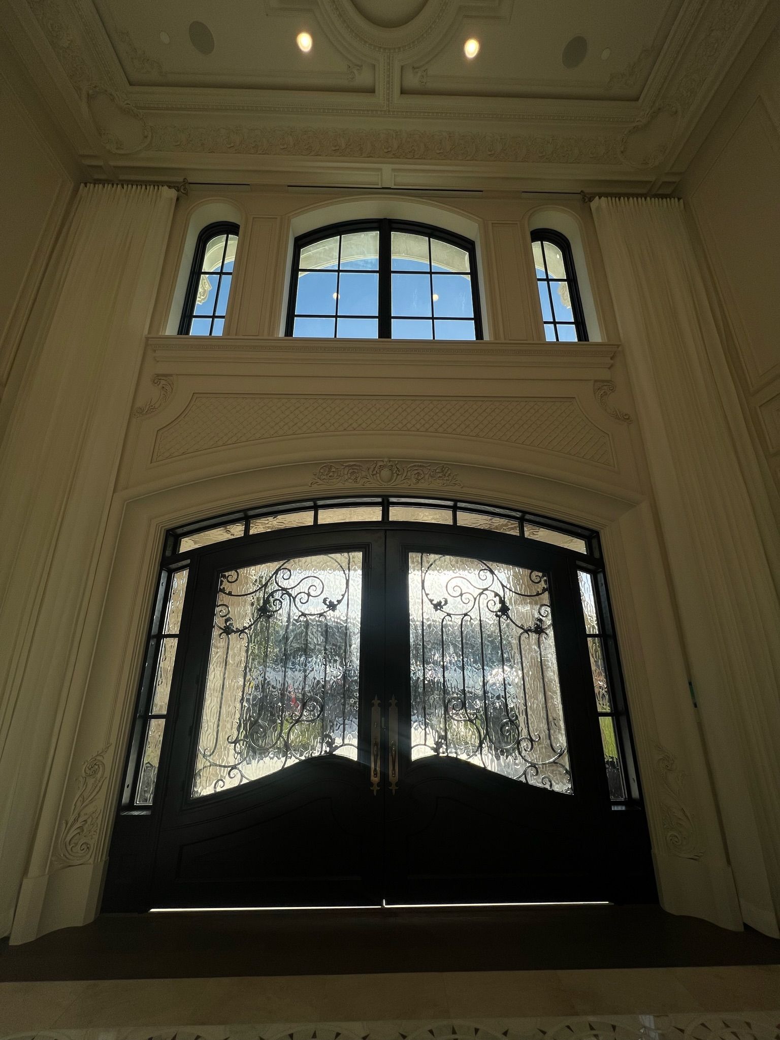 French design entryway with double height ceiling and door, architectural detailing and millworker, French style entrance.