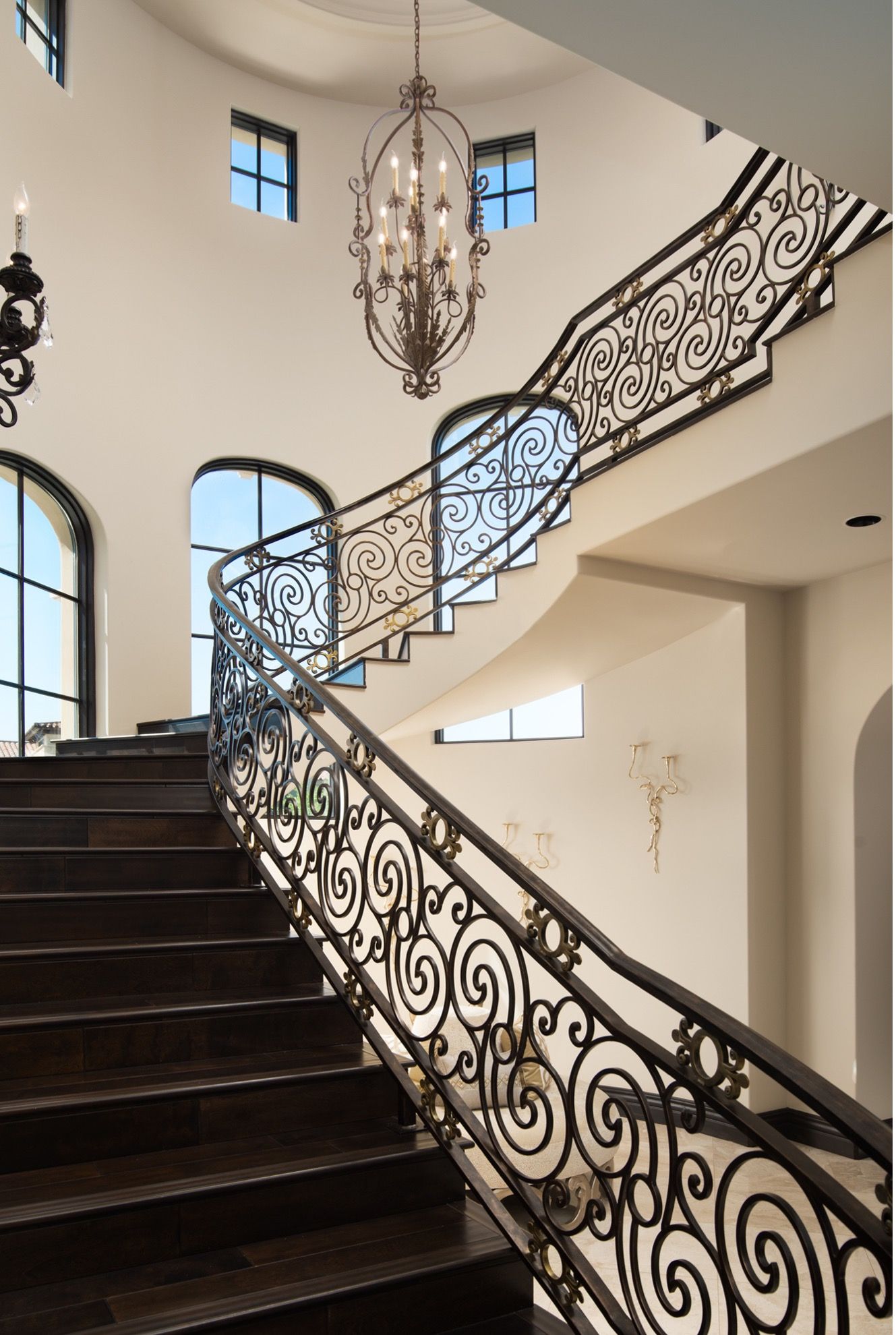 A staircase with a wrought iron railing and a chandelier hanging from the ceiling